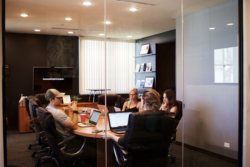 Two people shaking hands across a desk after a friendly business meeting.